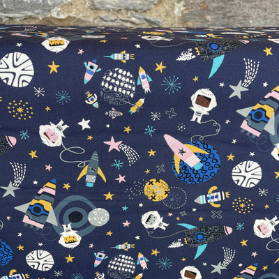 Navy cotton fabric with space themed design. Planets, spacemen, shooting stars, moons, rockets in pinks, yellows, turquoise and white. 