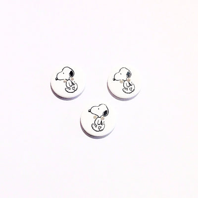 A round white button with Snoopy design printed in black on the front