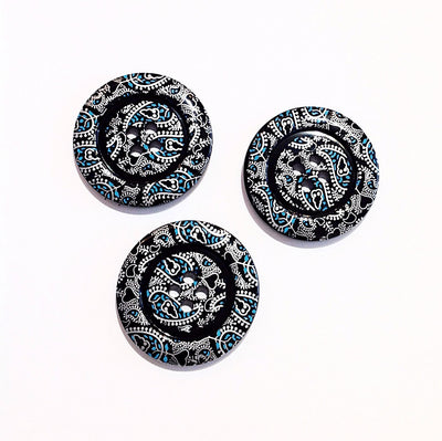 A black four holed button with a white and blue paisley pattern